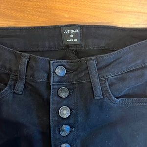 Black skinny button front jeans with frayed hem.